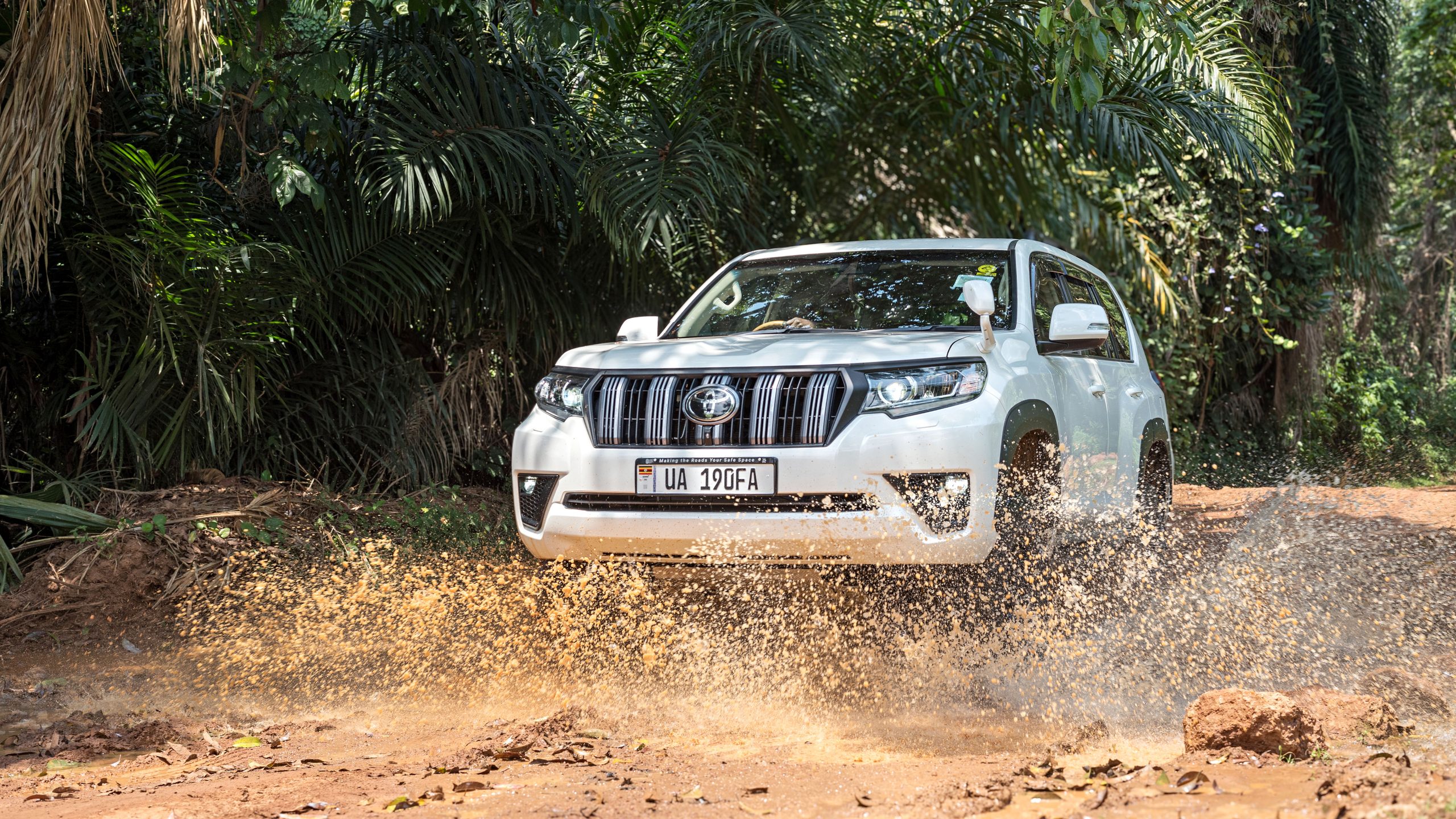 Toyota Land Cruiser Prado driving through a muddy forest track in Uganda