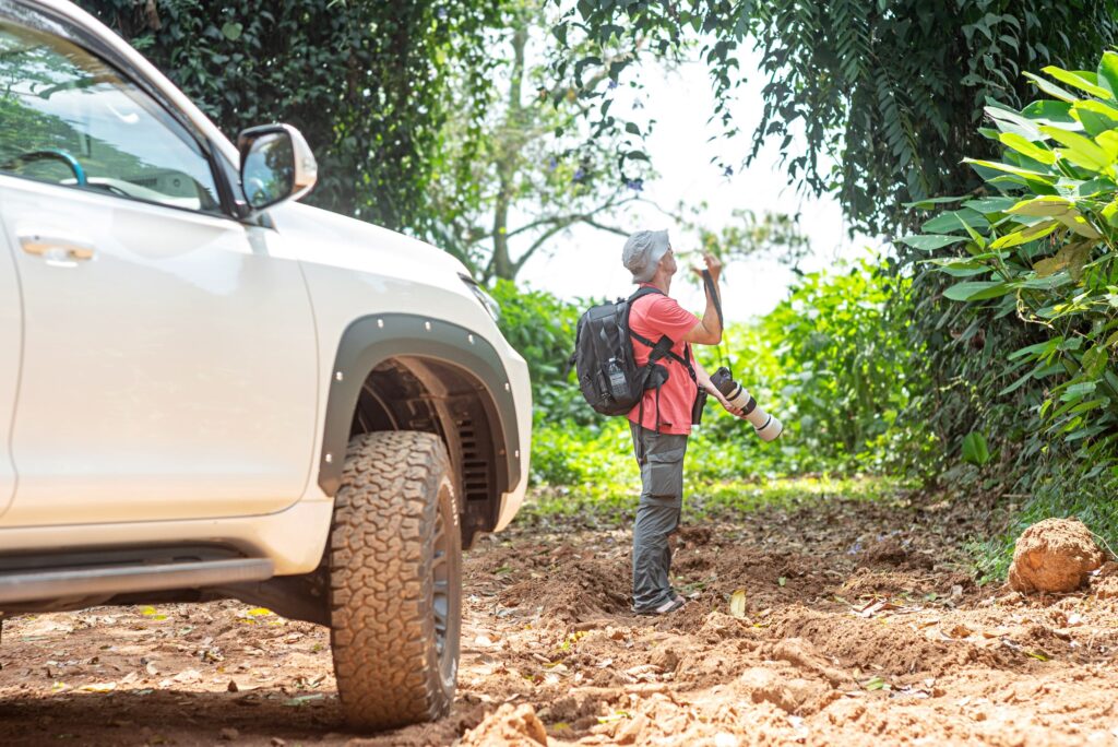 Traveller with binoculars next to the Land Cruiser